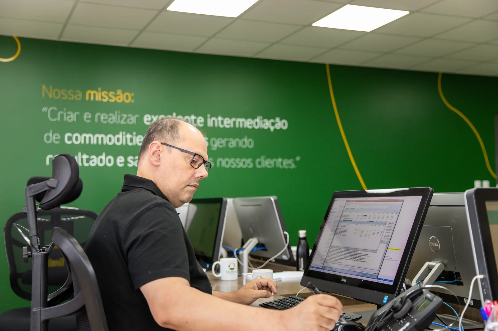 Equipe da Moema em plena negociação no escritório, diante da parede com a missão da empresa
