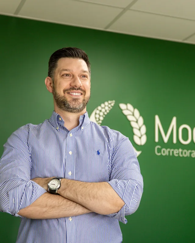 Broker da Moema diante da marca da empresa no escritório